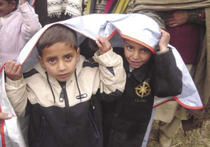 Two children share a heat blanket following an earthquake in Pakistan