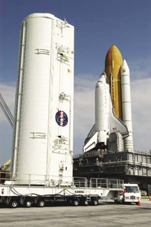 Space Shuttle Discovery on launch pad with large payload canister beside it