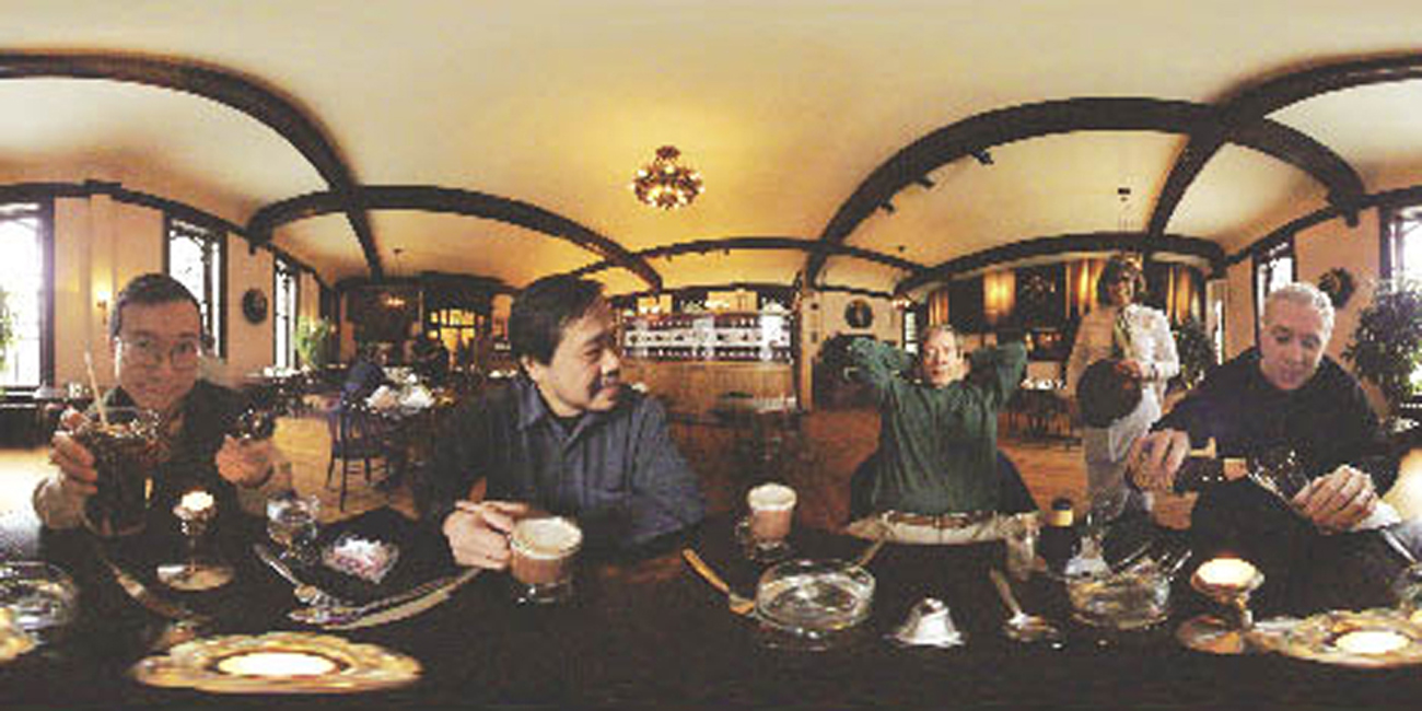 Wide photograph showing several people sitting together at a long table