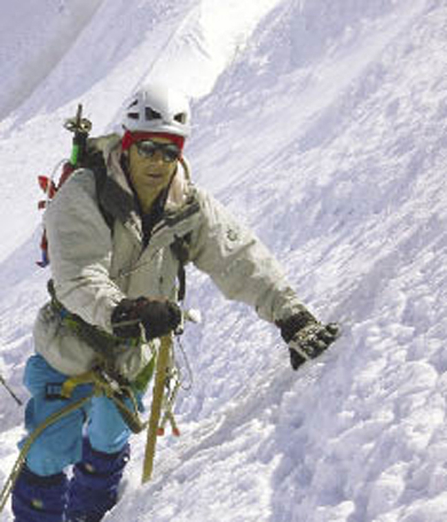 A mountain climber leans on a snowy slope.