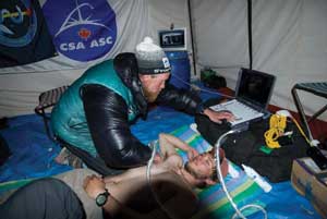 A mountain climber examines a colleague with ultrasound equipment. 