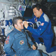 An astronaut holds an ultrasound device to another astronaut’s eyes.