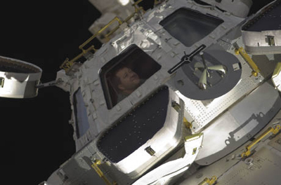 Astronaut looking out cupola window on the International Space Station Astronaut looking out cupola window on the International Space Station