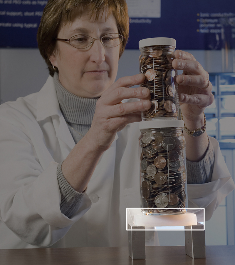 NASA scientist Mary Ann Meador stacks jars of coins on a piece of aerogel