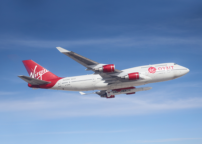 Virgin Orbit’s specially equipped Boeing 747 flies in blue skies with small rocket attached underneath