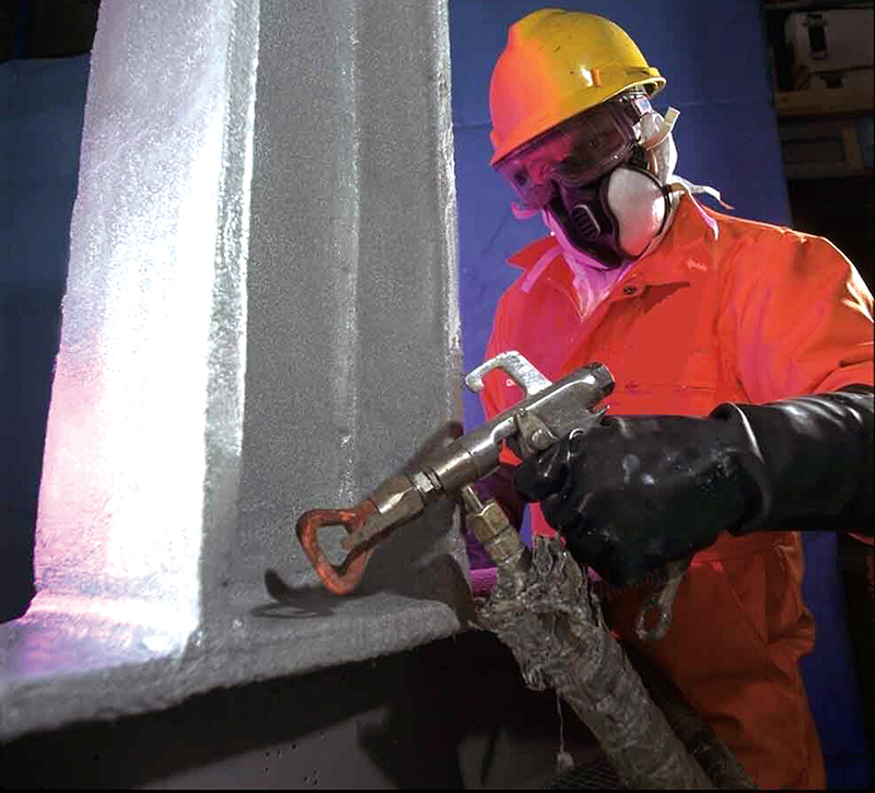 A worker in protective clothing sprays a fire resistant coating onto a steel beam