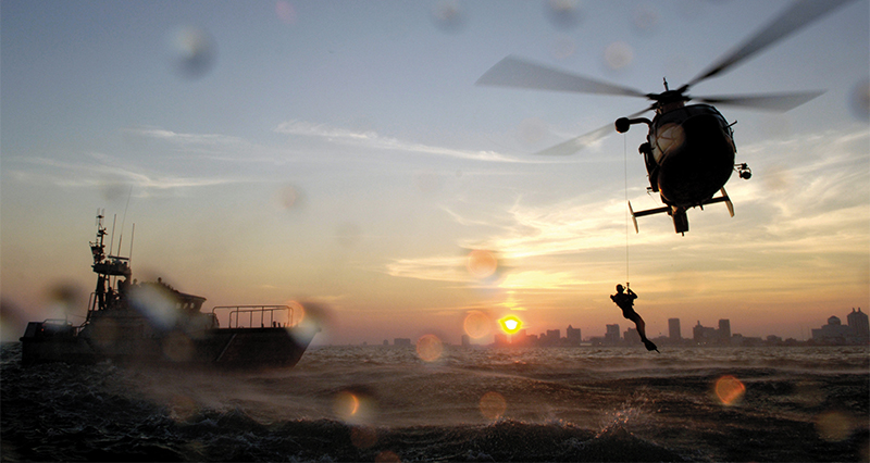 Rescue swimmer lowered by helicopter line to rough waters