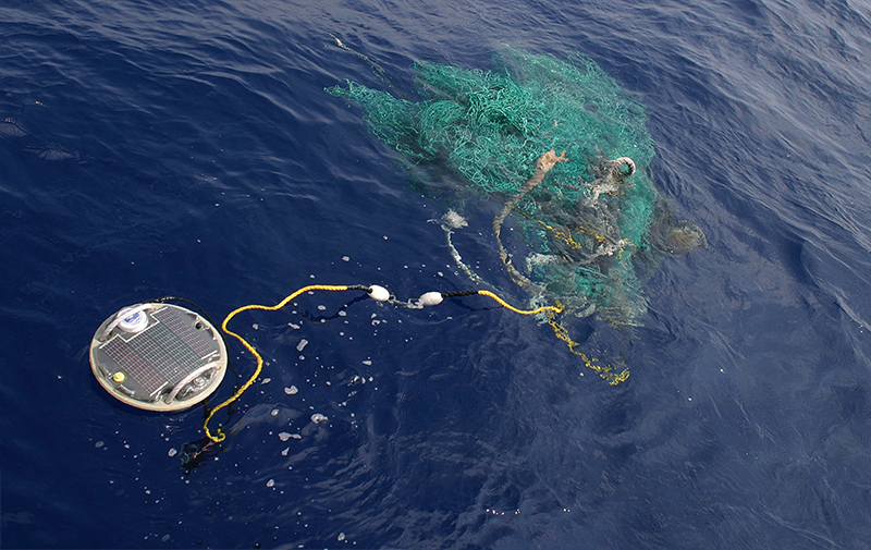 An Airborne Technologies buoy floats on the ocean’s surface near a ghost net