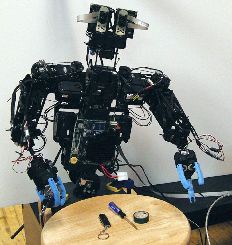 A humanoid robot lifting a tool from a table