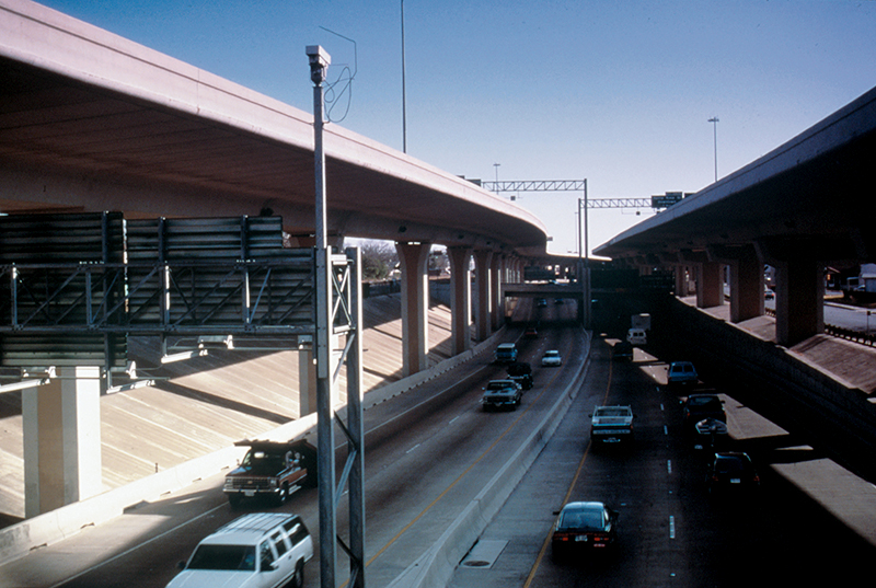 A highway with overpasses and poles with cameras