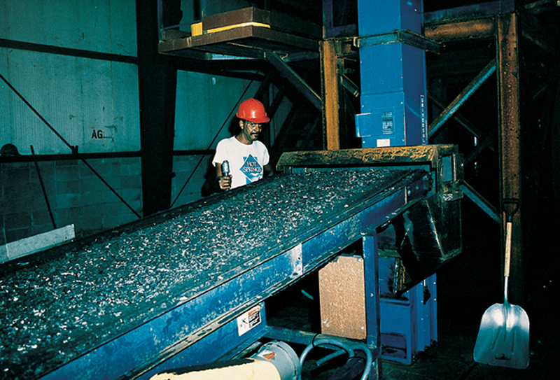 A worker with recycled tire crumbs on conveyer belt