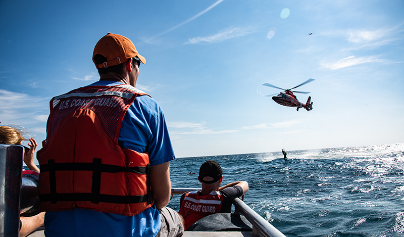Men on a rescue boat with a helicopter overhead