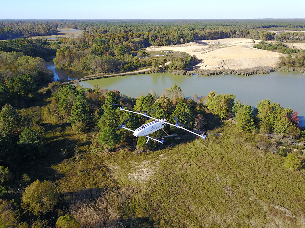 The Hybrid Advanced Multi-Rotor Aircraft flying over a treed area