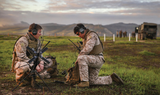 Two male servicemembers set up communications equipment in the field