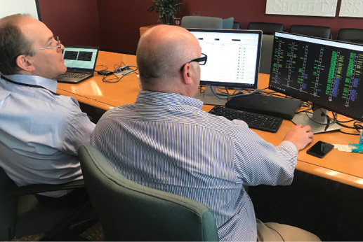 Mosaic CEO Chris Brinton and a retired air traffic coordinator look at a computer