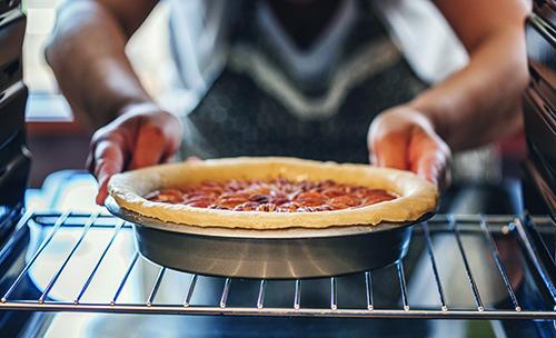 A woman removes a pie from the oven