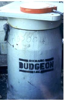 A comparison photo of the NASA technology load cell sitting atop the much larger 3000-pound standard hydraulic jack of the same lifting capacity