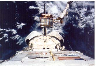 photograph of the Orbiter Endeavour's stern with the Spartan 207 free flyer being recaptured after a research trip