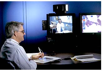 A doctor views a blood slide that was transmitted through video relay