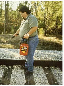 A man sprays railroad track with a special lubricant