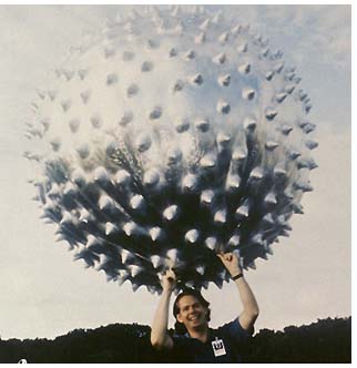 of a man in the grass holding the Jimsphere, which looks like a large spiny metallic ball above his head