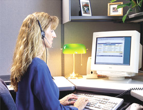 a sales woman sitting at a computer with a headset on, using the software in the office