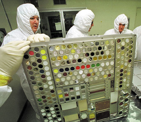 Clean room personnel place material samples into trays to be installed in the Passive Experiment Containers