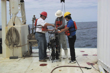 post doctoral student and a crew member in preparing a bio optics package for underwater data collection