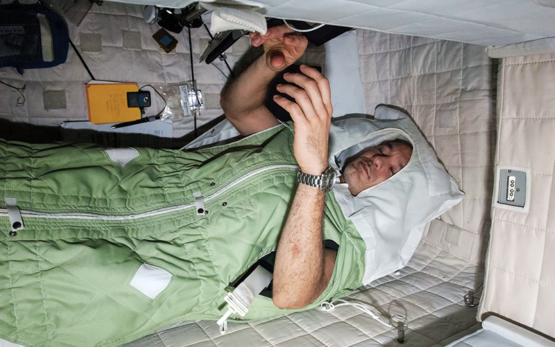 An astronaut zipped into a sleeping bag on the International Space Station