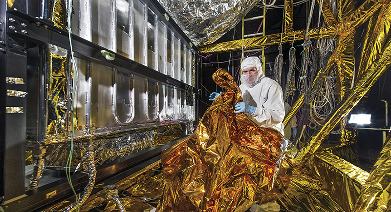 An engineer covers wires at Goddard Space Flight Center with radiant barrier insulation