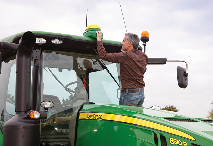 Man installing GPS navigation device on John Deere tractor