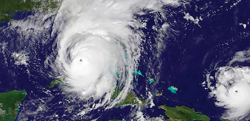 A satellite image of a massive hurricane over land with a smaller hurricane off to the side over the ocean