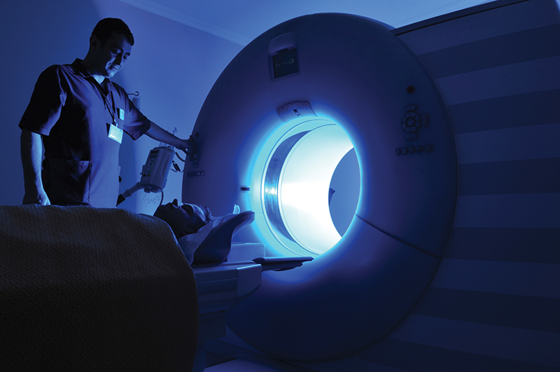 A technician prepares a patient to enter an MRI machine