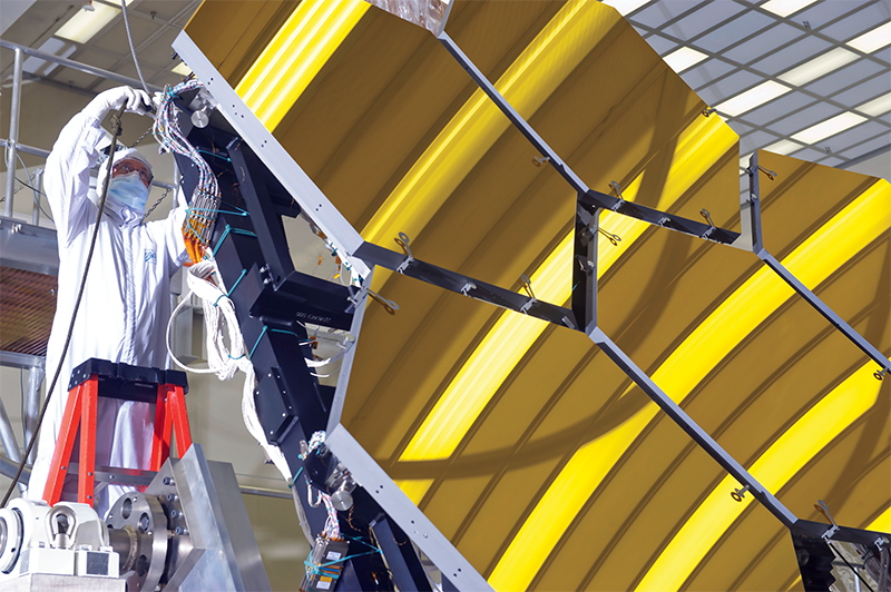 Engineer in clean suit works on the James Webb Space Telescope mirror installation