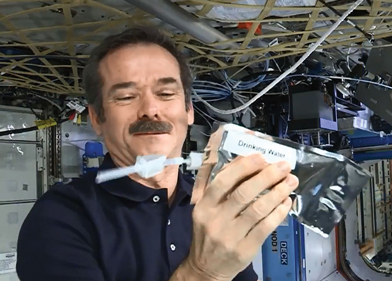 An astronaut examines water recycling equipment