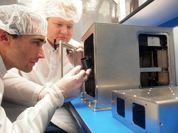 Engineers work on a 3D printer in a clean room