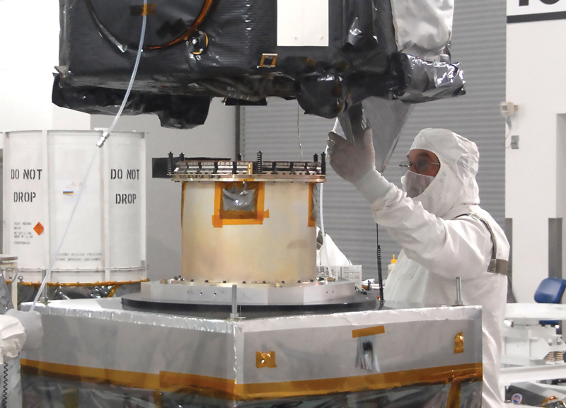 Engineer in clean room gear attaches spacecraft to separation device