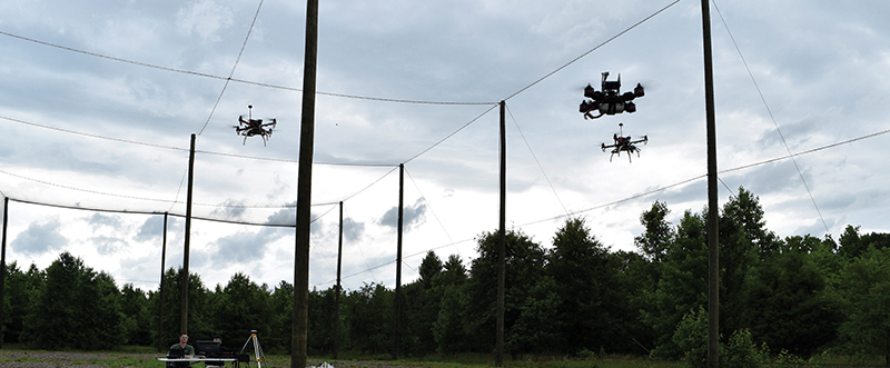 Three small drones fly above a field