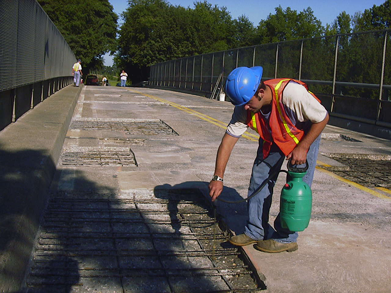 Worker applying liquid to rebar