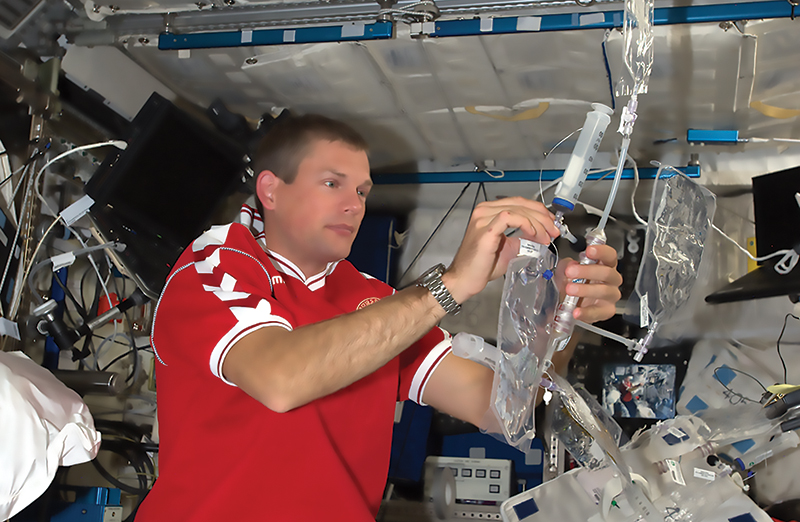 An astronaut on the space station works with the prototype water purification system based on membranes infused with aquaporins