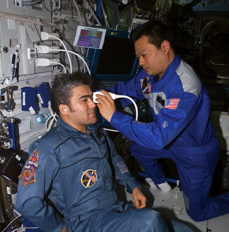 Astronauts using remote ultrasound equipment