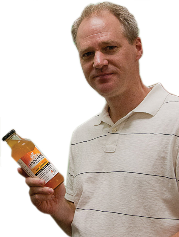 Mike Johnson holding a bottle of Unpeeled fruit drink