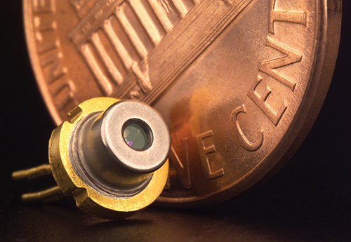 Miniaturized tunable diode laser next to a much larger but actual size penny