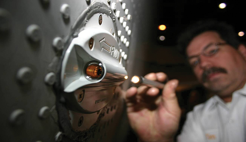 An engineer inspects the air sampling device mounted on the side of an airplane