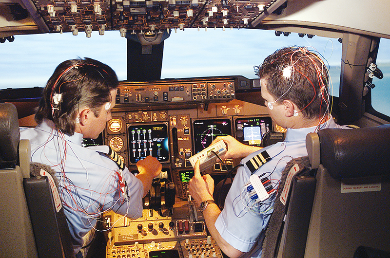 Two aircraft pilots in cockpit with sensors on them to monitor flight fatigue