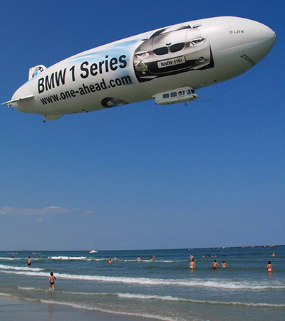 A blimp floats over a crowded beach