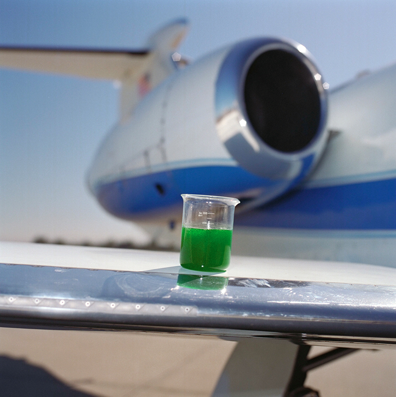 Green anti-icing liquid is pictured here in a glass on top of an airplane wing