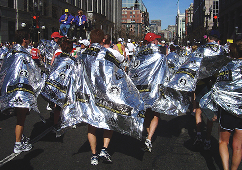 Marathon runners draped in reflective blankets to keep them warm