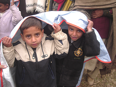 Two children share a heat blanket following an earthquake in Pakistan