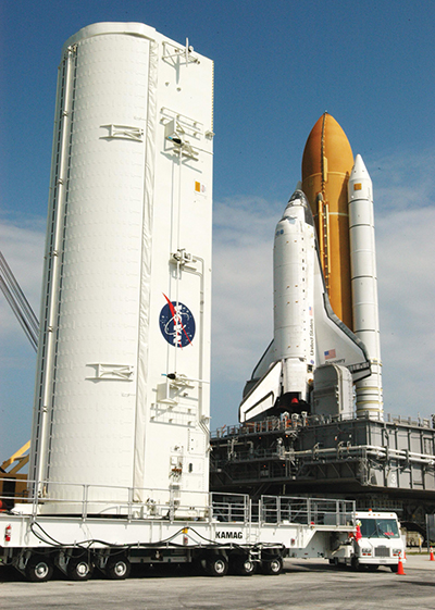 Space Shuttle Discovery on launch pad with large payload canister beside it